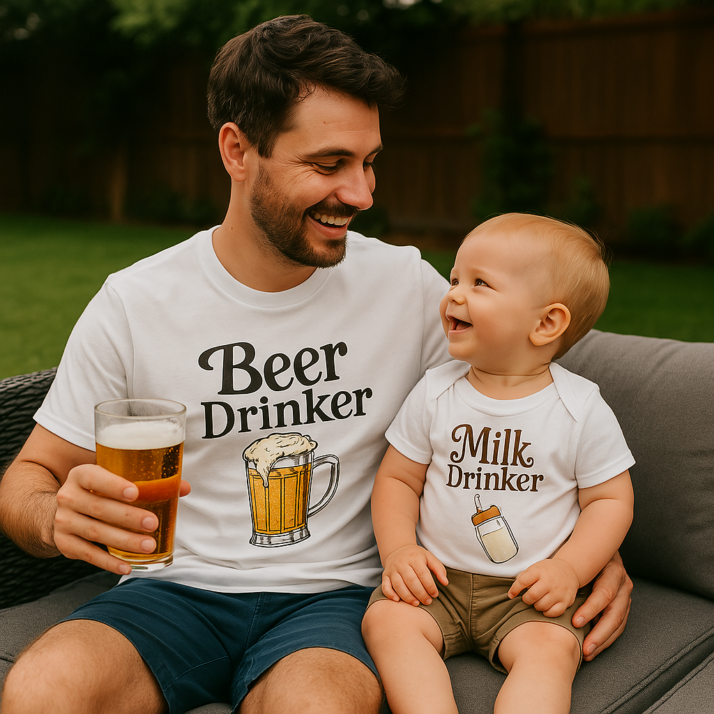 Smiling dad in “Beer Drinker” T-shirt holding a beer, with baby in “Bottle Drinker” onesie, sitting in a garden. Matching Fathers Day Gift.